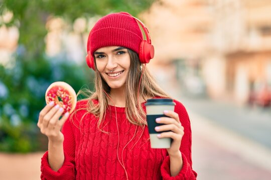 Young hispanic woman having breakfast using headphones at the city.