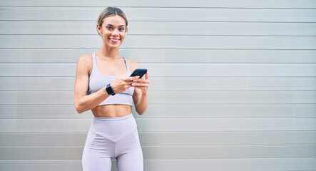 Young cauciasian fitness woman wearing sport clothes training outdoors using smartphone