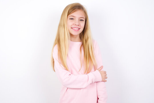 beautiful caucasian little girl wearing pink hoodie over white background laughing.