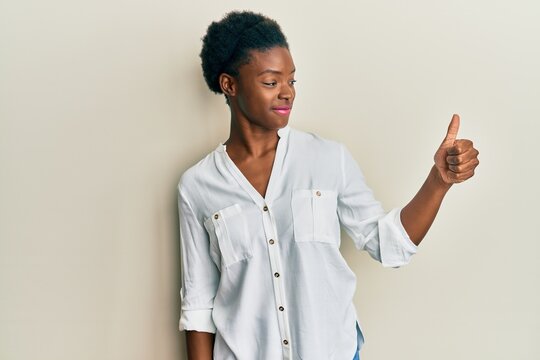 Young african american girl wearing casual clothes looking proud, smiling doing thumbs up gesture to the side