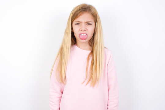 Body Language. Disgusted Stressed Out Beautiful Caucasian Little Girl Wearing Pink Hoodie Over White Background, Frowning Face, Demonstrating Aversion To Something.