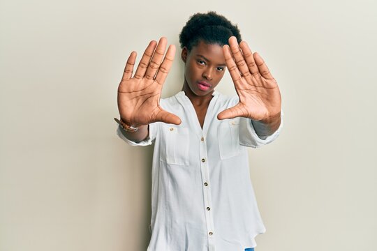 Young african american girl wearing casual clothes doing frame using hands palms and fingers, camera perspective