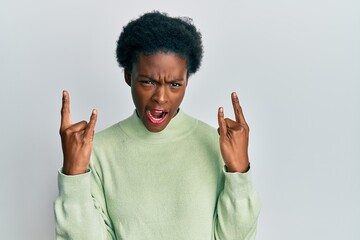Young african american girl wearing casual clothes shouting with crazy expression doing rock symbol with hands up. music star. heavy concept.