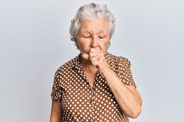 Senior grey-haired woman wearing casual clothes feeling unwell and coughing as symptom for cold or...