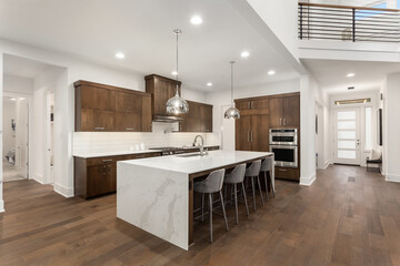 Beautiful kitchen in new modern luxury home with large waterfall island, stainless steel appliances, and view of entry