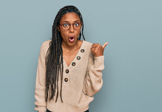 African american woman wearing casual clothes surprised pointing with hand finger to the side, open mouth amazed expression.