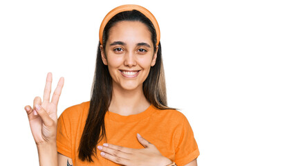 Young hispanic woman wearing casual clothes smiling swearing with hand on chest and fingers up,...
