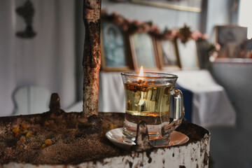 candle in glass  in an old chapel. wishing  candle in a glass on an iron table in an old orthodox chapel with religious icons