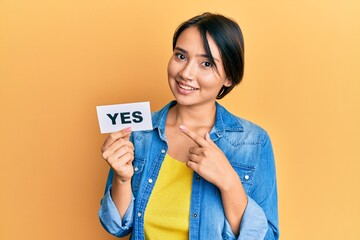 Beautiful young woman with short hair holding yes reminder smiling happy pointing with hand and...