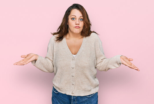 Young plus size woman wearing casual clothes clueless and confused expression with arms and hands raised. doubt concept.