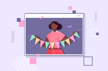 woman celebrating online birthday girl in computer window holding colorful paper bunting party flags