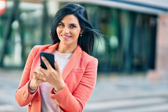 Young beautiful businesswoman smiling happy using smartphone at the city.