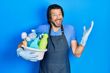 Middle age caucasian man holding cleaning products celebrating victory with happy smile and winner expression with raised hands