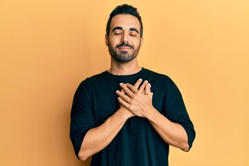 Young hispanic man wearing casual clothes smiling with hands on chest, eyes closed with grateful gesture on face. health concept.