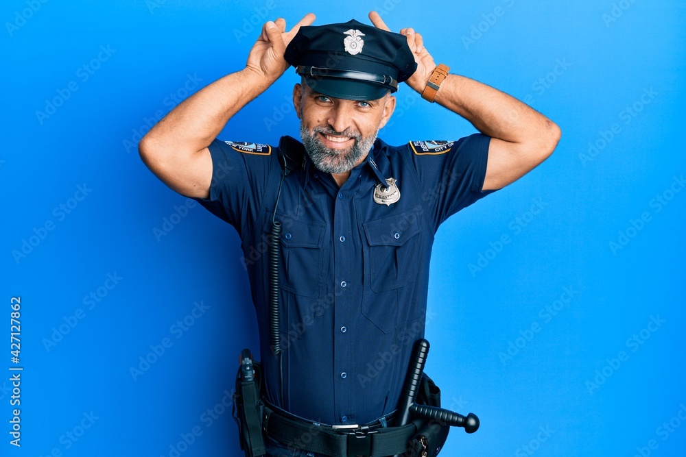 Wall mural Middle age handsome man wearing police uniform posing funny and crazy with fingers on head as bunny ears, smiling cheerful