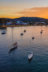 Obraz premium Aerial sunrise waterscape over the channel with orange clouds and boats below