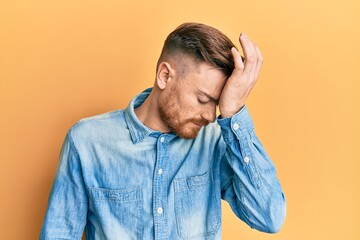 Young redhead man wearing casual denim shirt surprised with hand on head for mistake, remember...