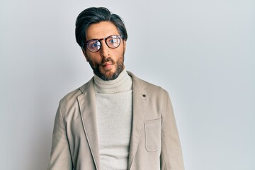 Young hispanic man wearing business jacket and glasses making fish face with lips, crazy and comical gesture. funny expression.
