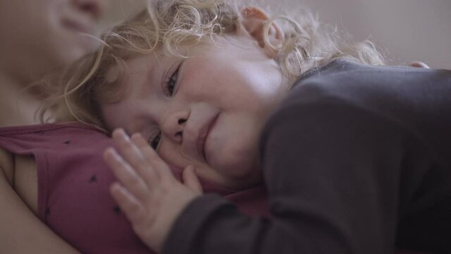 a disgruntled child lies on his mother's chest