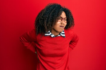 Fototapeta na wymiar Beautiful african american woman with afro hair wearing sweater and glasses suffering of backache, touching back with hand, muscular pain
