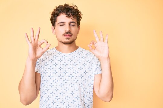 Young caucasian man with curly hair wearing casual clothes relax and smiling with eyes closed doing meditation gesture with fingers. yoga concept.