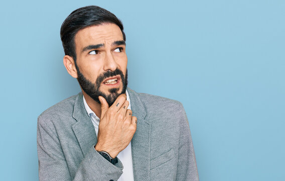 Young hispanic man wearing business clothes thinking worried about a question, concerned and nervous with hand on chin