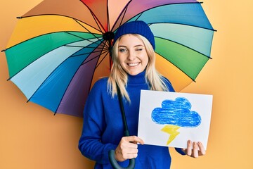 Young caucasian woman holding rain draw and umbrella winking looking at the camera with sexy...
