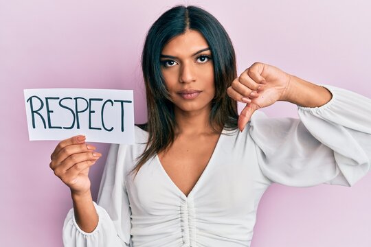 Young latin transsexual transgender woman holding respect message paper with angry face, negative sign showing dislike with thumbs down, rejection concept