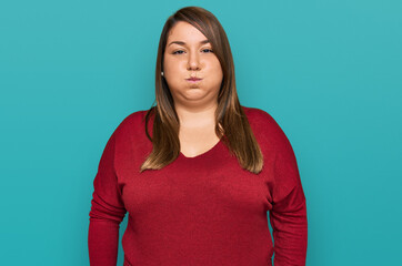 Beautiful brunette plus size woman wearing casual clothes puffing cheeks with funny face. mouth...