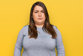 Beautiful brunette plus size woman wearing casual clothes skeptic and nervous, frowning upset...