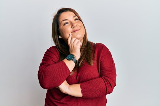 Beautiful brunette plus size woman wearing casual clothes thinking concentrated about doubt with finger on chin and looking up wondering