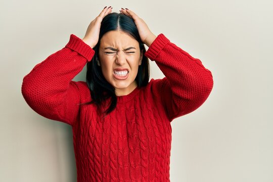 Beautiful brunette woman wearing wool winter sweater suffering from headache desperate and stressed because pain and migraine. hands on head.