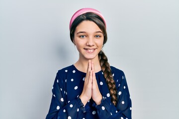 Young brunette girl wearing elegant look praying with hands together asking for forgiveness smiling confident.