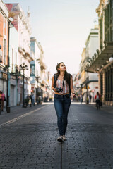 young woman walking in the middle of the street at sunset