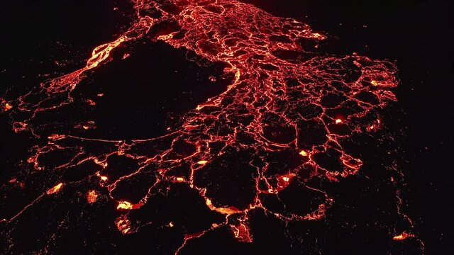 Aerial drone view over a lava texture glowing red in the dark,erupting Volcano