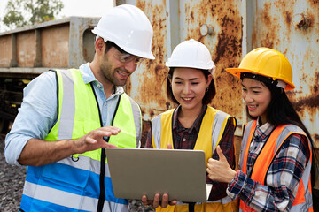 Rail logistics engineers are discussing outdoor with laptops.