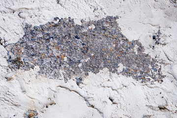 A close-up of a black-spotted cinder block wall filled with cement mortar along the edges.