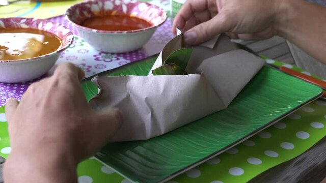 Man unpack a package of nasi lemak or Malaysia fragrant rice cooked in coconut milk added with chilly.