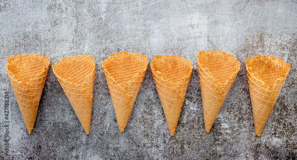 Poster Flat lay ice cream cones collection on dark stone background . Blank crispy ice cream cone with copy space for sweets menu design.