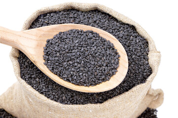 Seeds of black sesame in a sack of isolated on a white background. Black sesame in a burlap sack. Healthy food. Black sesame in a jute bag. Vegan food