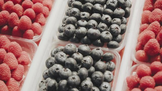 On counter in store are feijoa, strawberries, cherries, blueberries and raspberries. Camera moves from right to left. Concept of vegetarianism and consumption of fresh fruit and berries