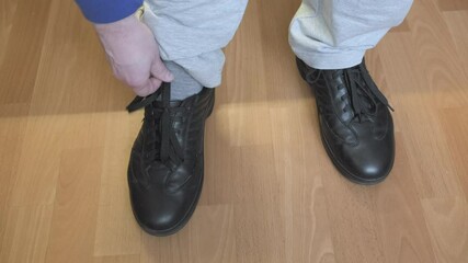 Man is limping, he rubbed his foot with tight shoes. Person takes off his shoes and touches the injured leg. The concept of foot pain due to uncomfortable, improper sized shoes