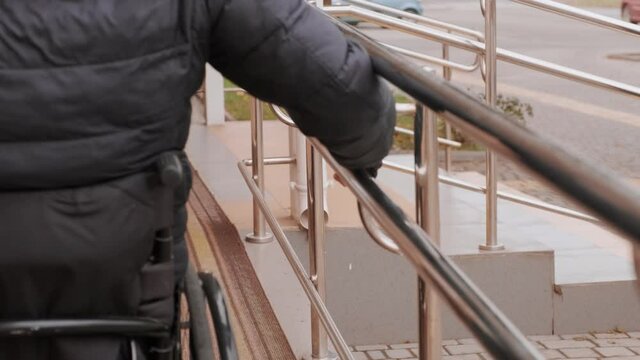 A person with a disability moves along the street in a wheelchair