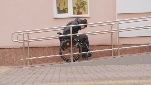A person with a disability moves along the street in a wheelchair