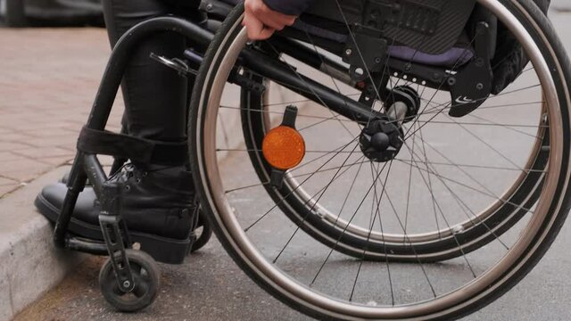 A person with a disability moves along the street in a wheelchair