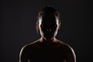 silhouette portrait of a beautiful young woman against dark backgroung.