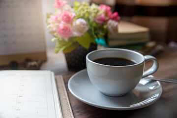 Coffee Break Time. A cup of coffee, diary, clock, calendar, and Rose Flower vase place on home office.