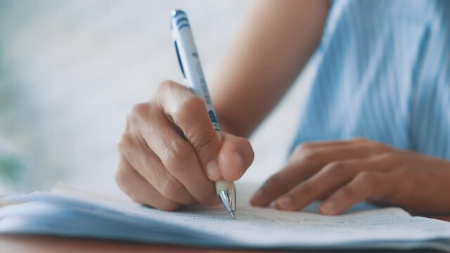 HD Close up hand of business women use pen writing document paper. Female hand close up writing with a blue pen on a white sheet. Woman writes information on a piece of paper.