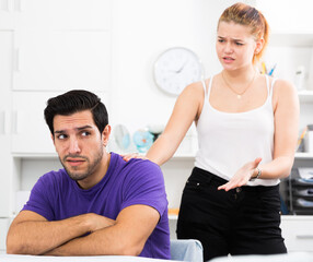 Young stressed man at home table with screaming wife behind