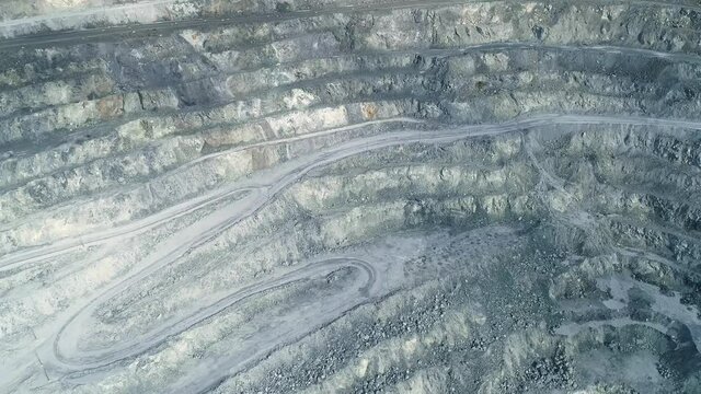 Aerial view of Huge asbestos quarry. Inside the quarry there is a serpentine road for trucks. In the center of the frame is a site loaded with explosives. The camera flies back and a panorama of the v